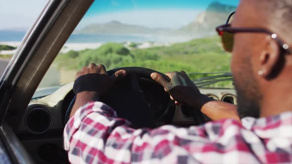 African american man with hands on steering wheel sitting in the convertible car on road alt