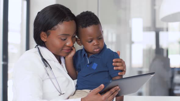 Doctor Showing Tablet Pc To Baby Patient at Clinic alt