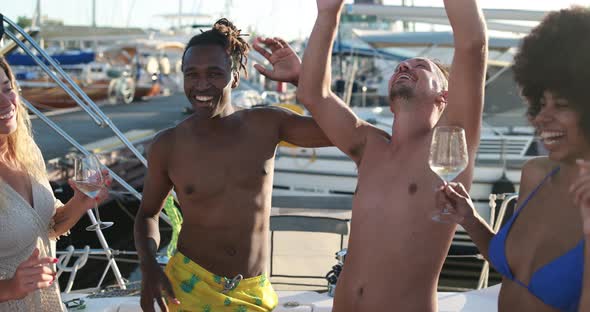 Happy multiracial friends having fun dancing and drinking champagne at boat party outdoor alt
