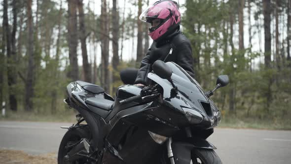 Confident Young Woman Approaching Motorbike, Sitting on It, and Closing Helmet Visor. Portrait of alt