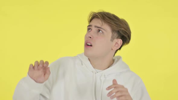 Young Man Feeling Scared Frightened on Yellow Background alt