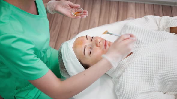 Girl Beautician Makes Facial Cleansing Procedure for Young Woman in Beauty Salon alt