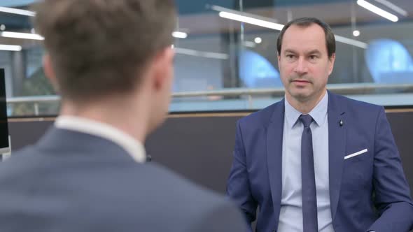 Rear View of Businessman Talking to Colleague in Office alt