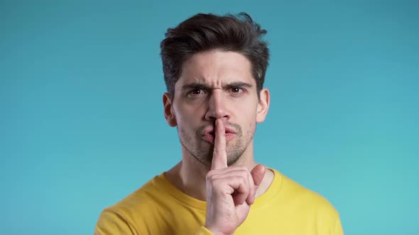 European handsome man holding finger on his lips over blue background. Gesture of shhh alt