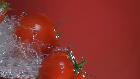 Wet Red Cherry Tomatoes are Flying Horizontally with the Splash of Water alt
