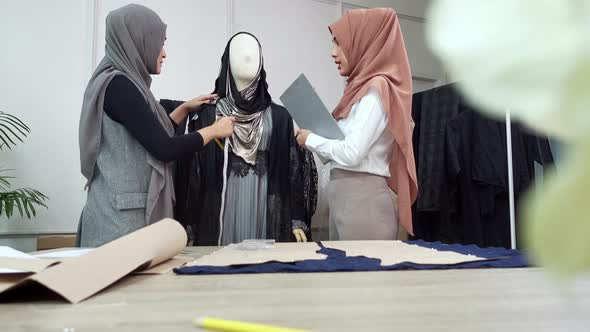 Muslim fashion designer measuring size of the dress working with her assitant in tailor shop