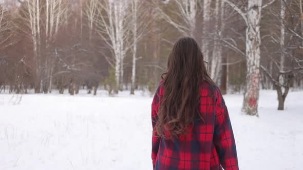 Female in Checkered Shirt Walking in Snowy Park