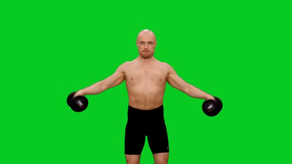 Adult Male Athlete Lifting Dumbbells During Workout against Green Screen