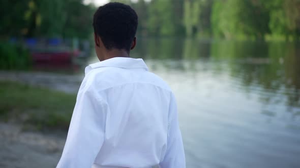 Smiling Relaxed African American Woman Walking on River Beach Smiling Stretching Hand Looking at alt
