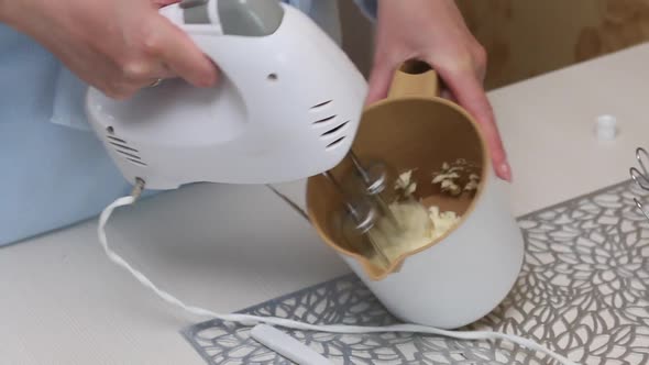 A Woman Whips Butter Into A Cream Using A Mixer. Baking Tray With Meringue For Cake alt