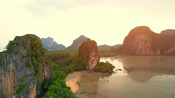 A view from a drone flying over rocky mountains and sandy beaches at low tide alt