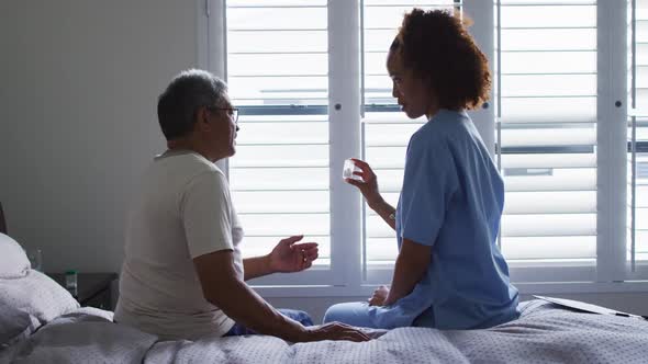 Senior mixed race man with female doctor talking and holding pills alt