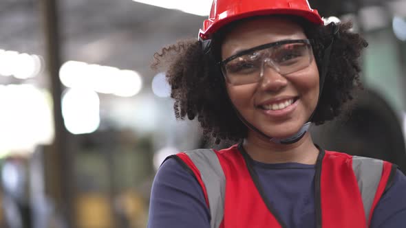 African American female factory worker in safety clothing smiling to camera