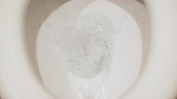 The Water is Flushed Into the White Toilet Close Up