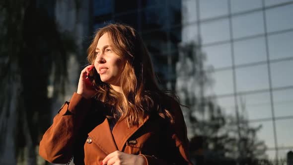 Young woman having phone call outdoors. Girl talking on the phone on the street alt