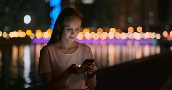 At Night a Young Girl Holds a Smartphone in Her Hands and Looks at the Screen alt