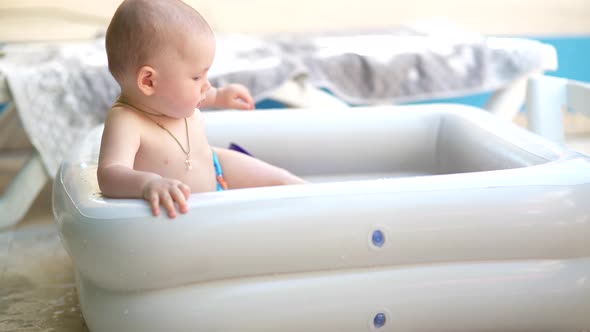 Cute Baby Boy Swimming and Playing with Toys in Inflatable Pool