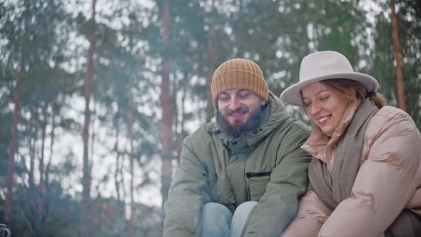 Couple is Warming Their Hands By a Campfire in the Woods in Winter