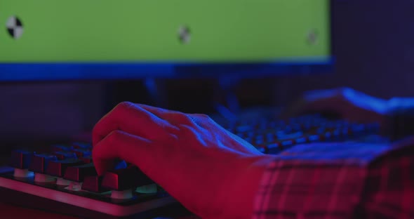 Hands of young gamer playing e-sport pressing on computer keyboard at night