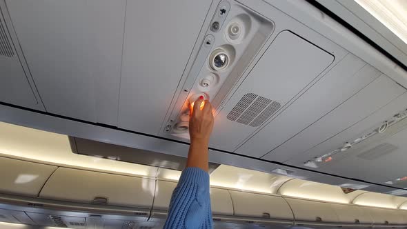 Girl Adjusts The Light In The Plane Cabin
