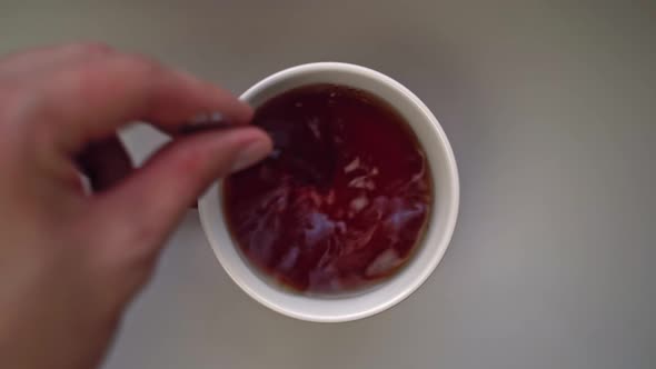 Top View of Man's Hand Pouring Spoonful of Sugar Into Mug of Tea