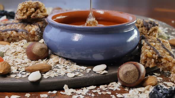 Dried Fruits Nuts Muesli Oat Flakes and Flowing Honey in a Clay Pot
