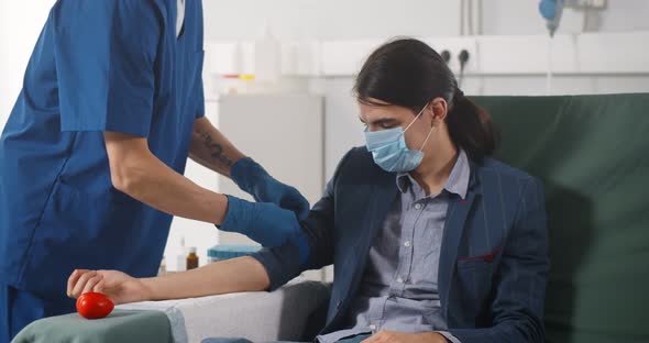 Portrait of Young Man Donor in Medical Mask Donating Blood in Laboratory alt