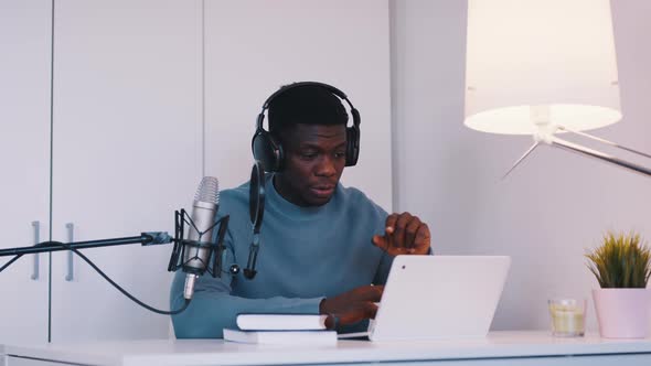 Man Wearing Headphones Doing an Online Meeting Using a Laptop and Microphone alt
