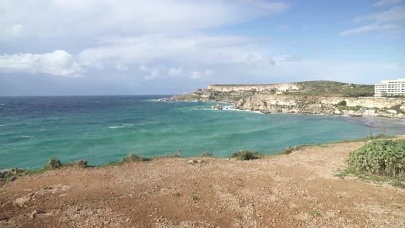 Sunny Day at Ghajn Tuffieha Bay with Mediterranean Sea Waves Rolling to Shore