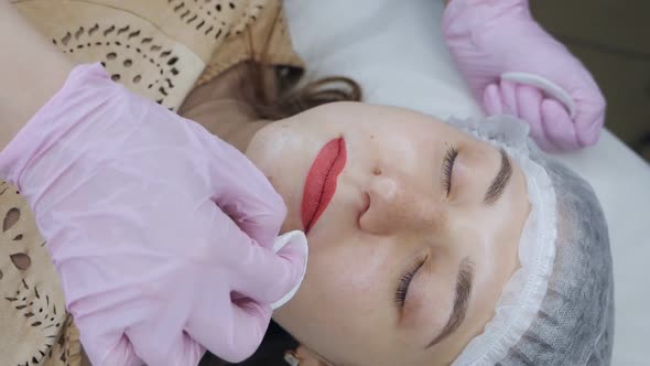 Cosmetologist in Pink Gloves Wipes Excess Red Pigment From Lips