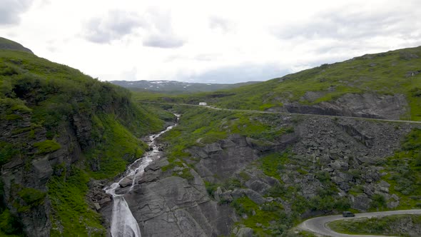 Vehicles Driving On Holesvingane Hairpin Turn In A Road Passing By River Flowing Into Waterfall In N alt
