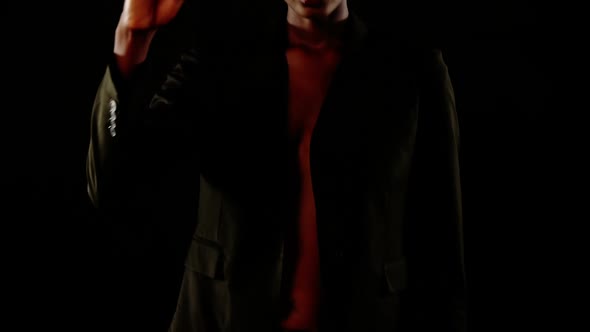 Androgynous man in blazer posing against black background alt