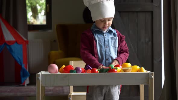 little boy plays cooking at table in home