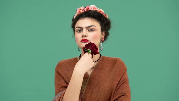 Fashion Portrait of Brunette Mexican Woman As Famous Artist Frida Kahlo Holding Red Big Rose and alt
