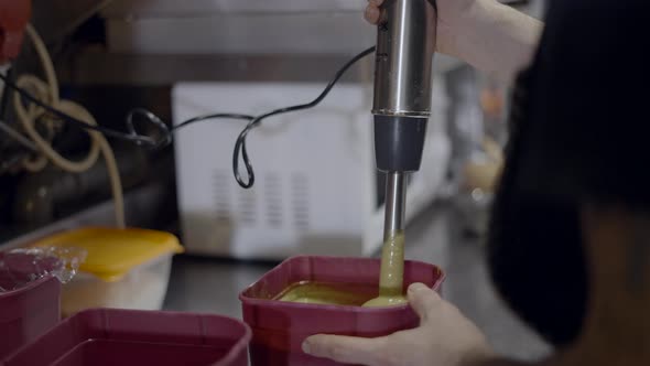 Close Side View of Immersion Blender Mixing Sauce in Plastic Container alt