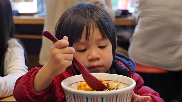 Cute Asian Child Eating Salmon Roe Rice Bowl  In A Japanese Restaurant  alt