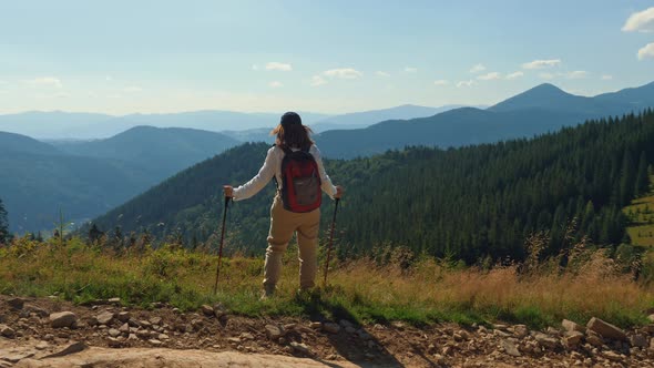Woman with Trekking Poles Standing on the Top of the Mountain