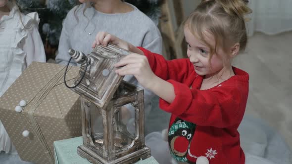 Happy American family celebrating Christmas. Children open a gift at home. alt