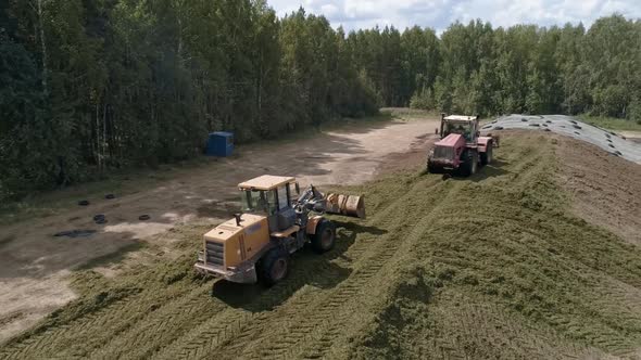 Drone view of tractors tamp the silage in the Silo Trench next to the forest 05 alt