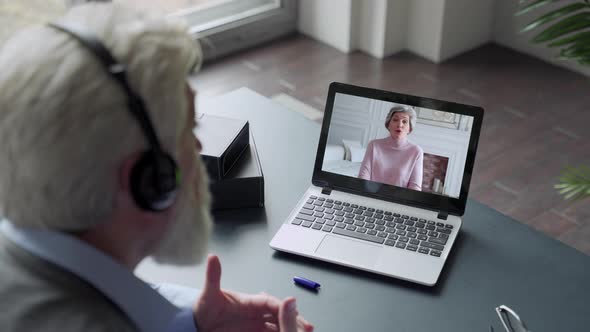 Over the Shoulder View of an Elderly Man Video Call To Wife Using a Laptop. The Concept of Family alt