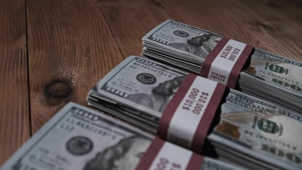 Three Stacks of 10000 American Dollars Banknotes in Bundles Lie on Wooden Table alt