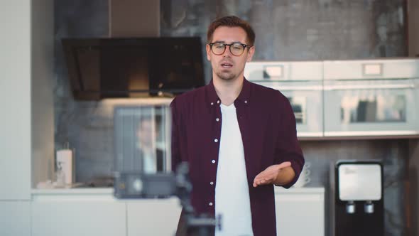 Young Hipster Man Standing in Modern Kitchen Recording Video for Internet Blog alt
