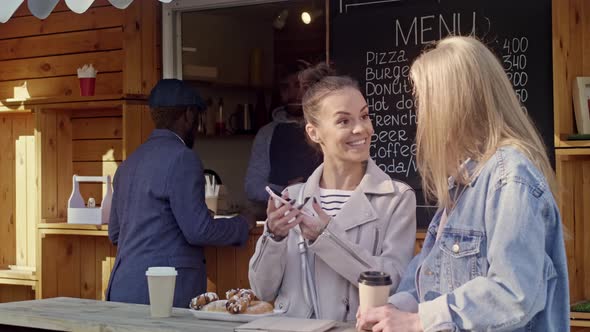 Smiling woman talking with her friend near food booth