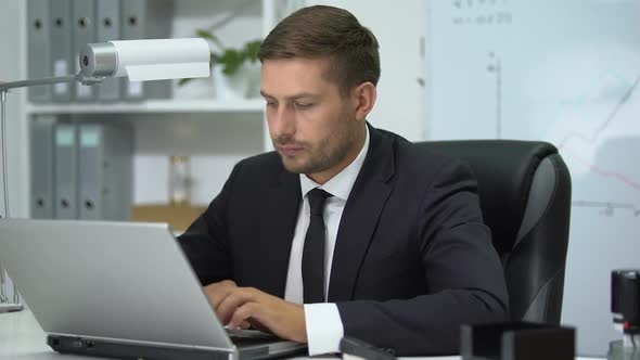 Attentive Businessman Working on Laptop Computer at Office, Modern Technologies