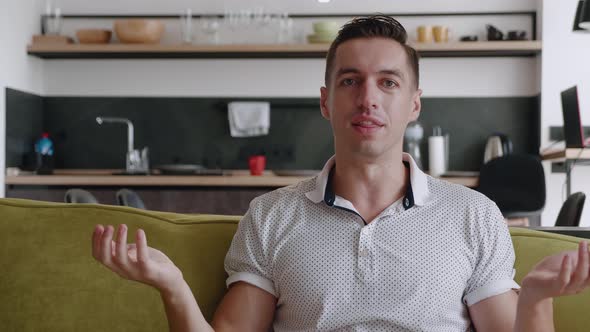 Smiling Young Man Making Video Call While Sitting on Couch in Living Room. Portrait of Happy Man alt