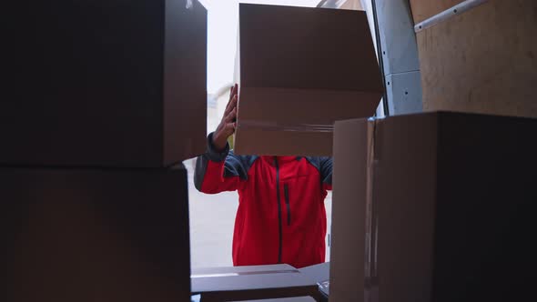 Young Courier Unloading Parcels From the Truck alt