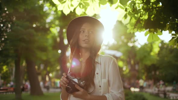 Young Beautiful Girl in Hat Photographing in City Park