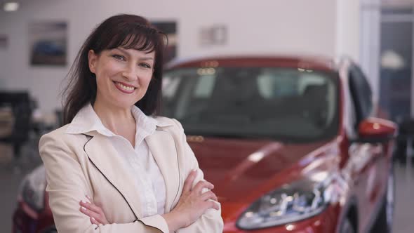 Elegant Confident Beautiful Woman Crossing Hands Smiling Looking at Camera Standing in Car alt