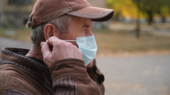 Close Up Portrait Elderly Man Puts a Medical Mask on His Face