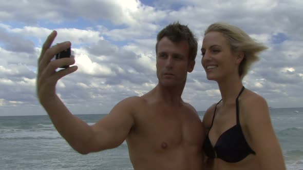 Male and female taking pictures of themselves with a digital camera alt